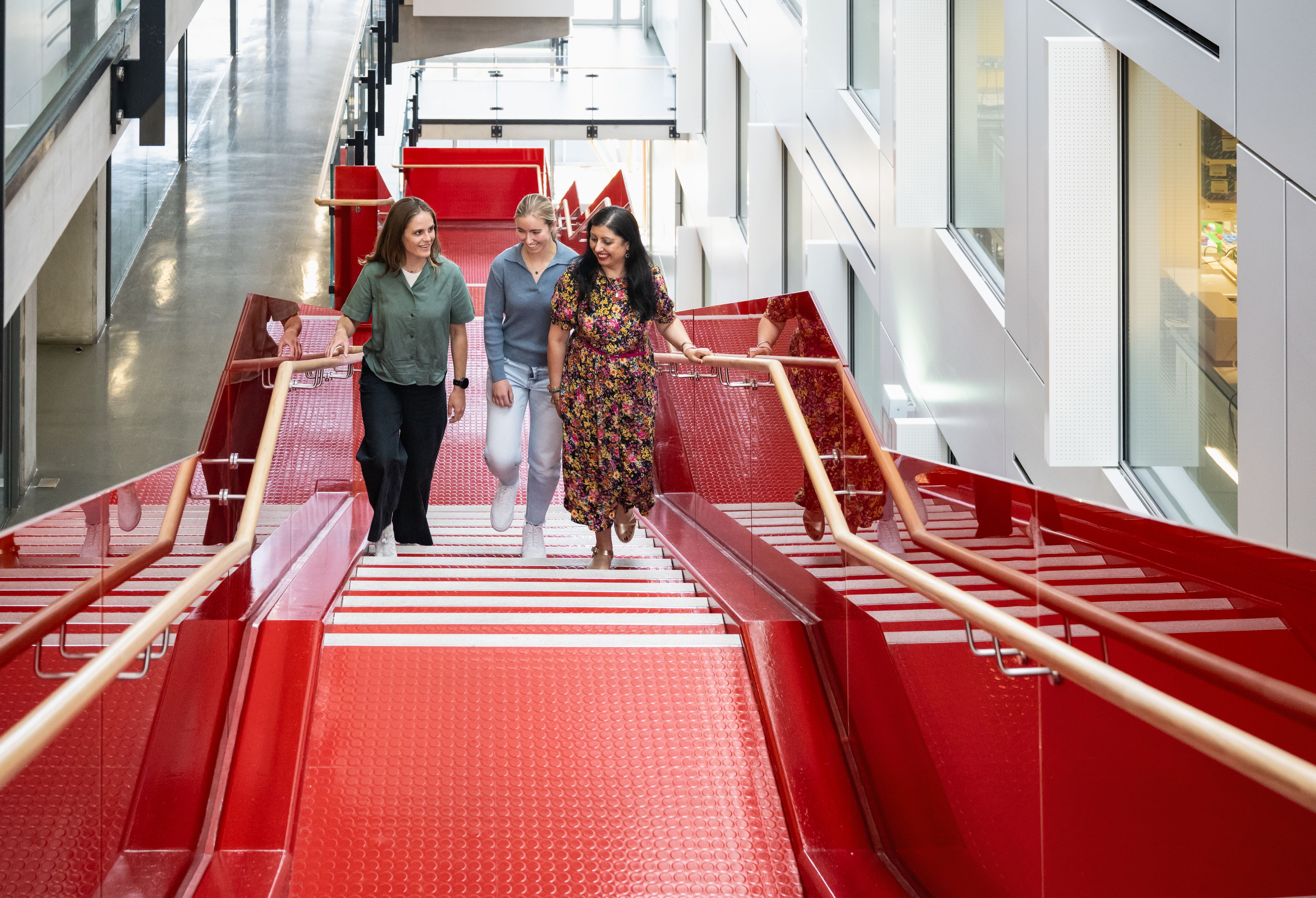The team of three walking up a red set of stairs